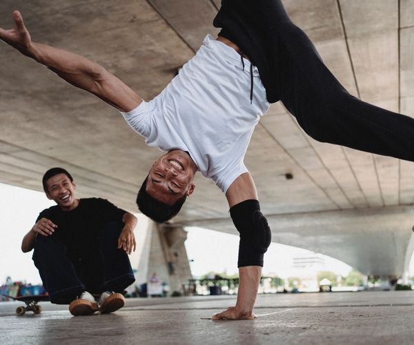 Two men outside laughing while one does a cartwheel 