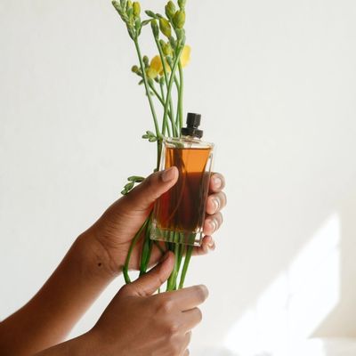 hands holding a flower and a bottle of perfume