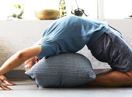 person stretching in backbend with pillow, clinical protection