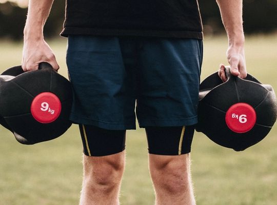 Man holding weights in a field, hand sweat