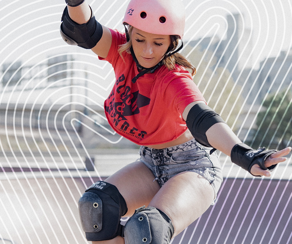 woman in pink helmet, crop top and shorts, skateboarding